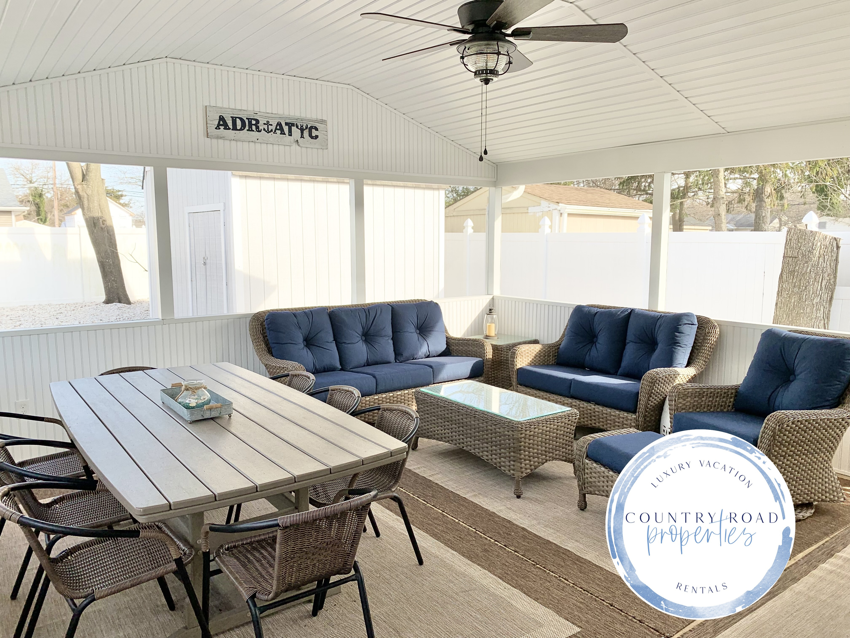 Experience the best of indoor-outdoor living in our screened-in sunroom. Kick back on navy wicker seating to watch the game or enjoy a meal at the large dining table—all while staying protected from the elements in a bright, coastal setting.