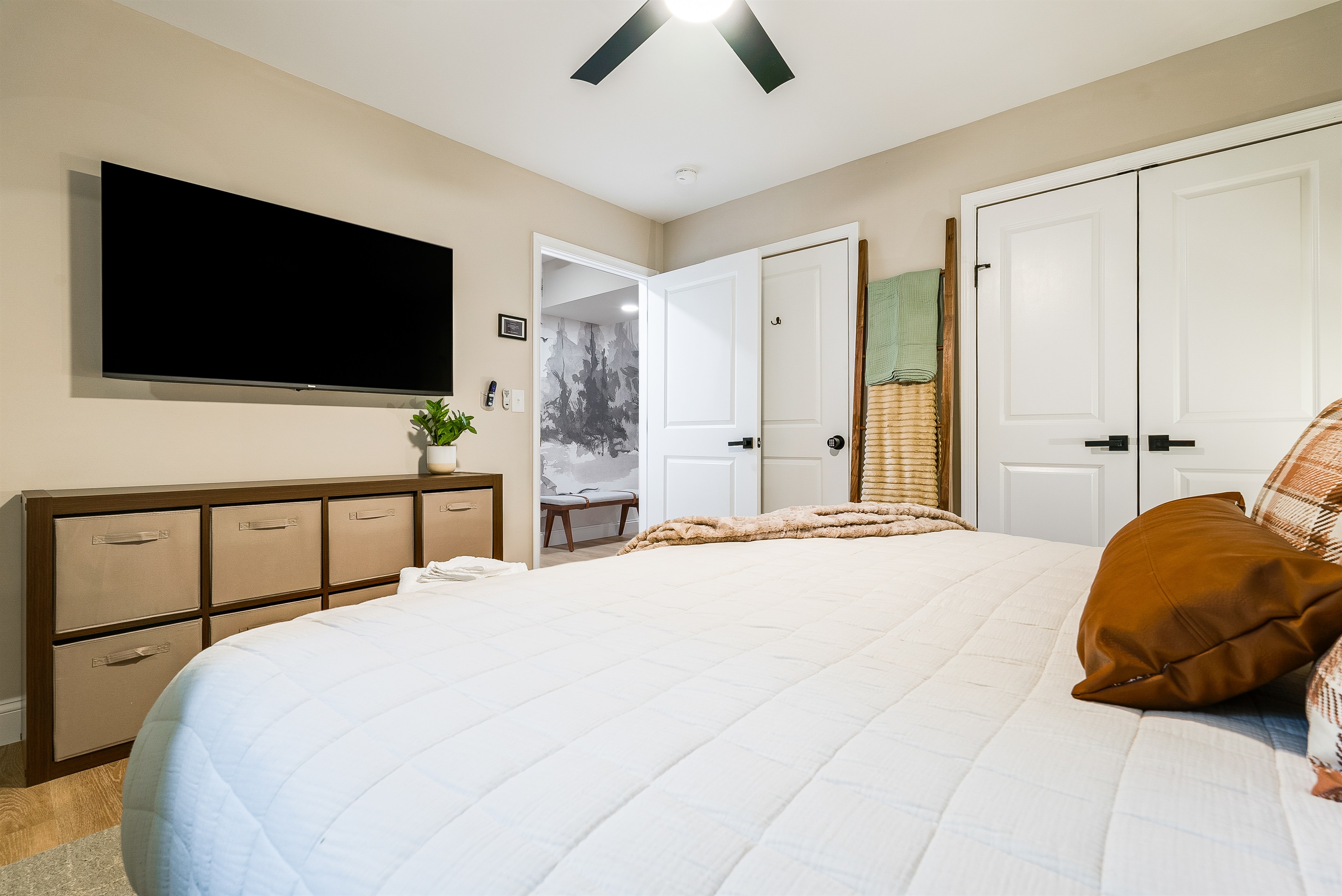 This inviting bedroom is designed for both comfort and convenience, featuring a large smart TV, storage for everyone’s essentials, and a warm, neutral palette. Ideal for parents who want to unwind with a movie after the kids are asleep down the hall.