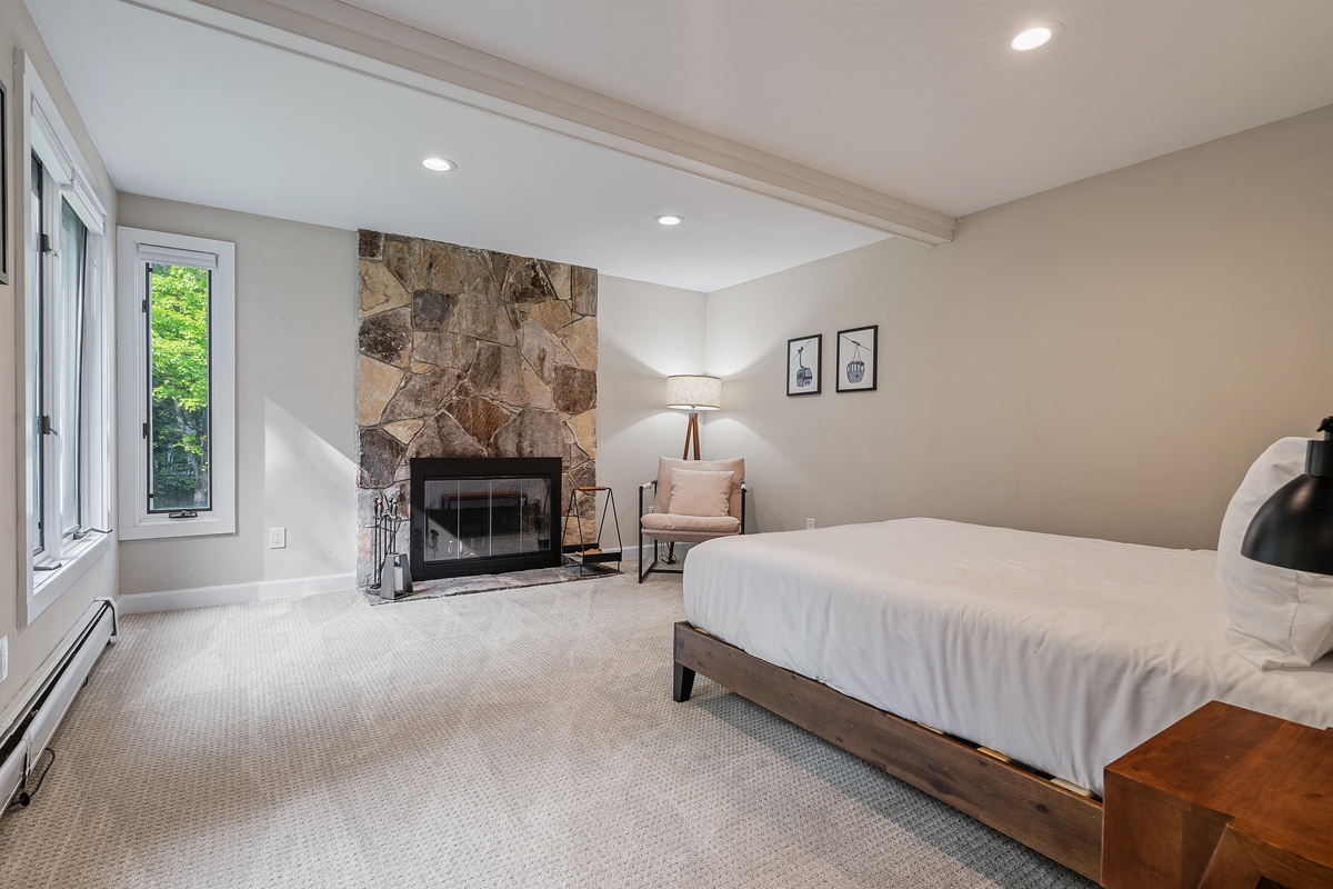 Bedroom with stone fireplace and queen bed at this Stratton Mountain vacation home