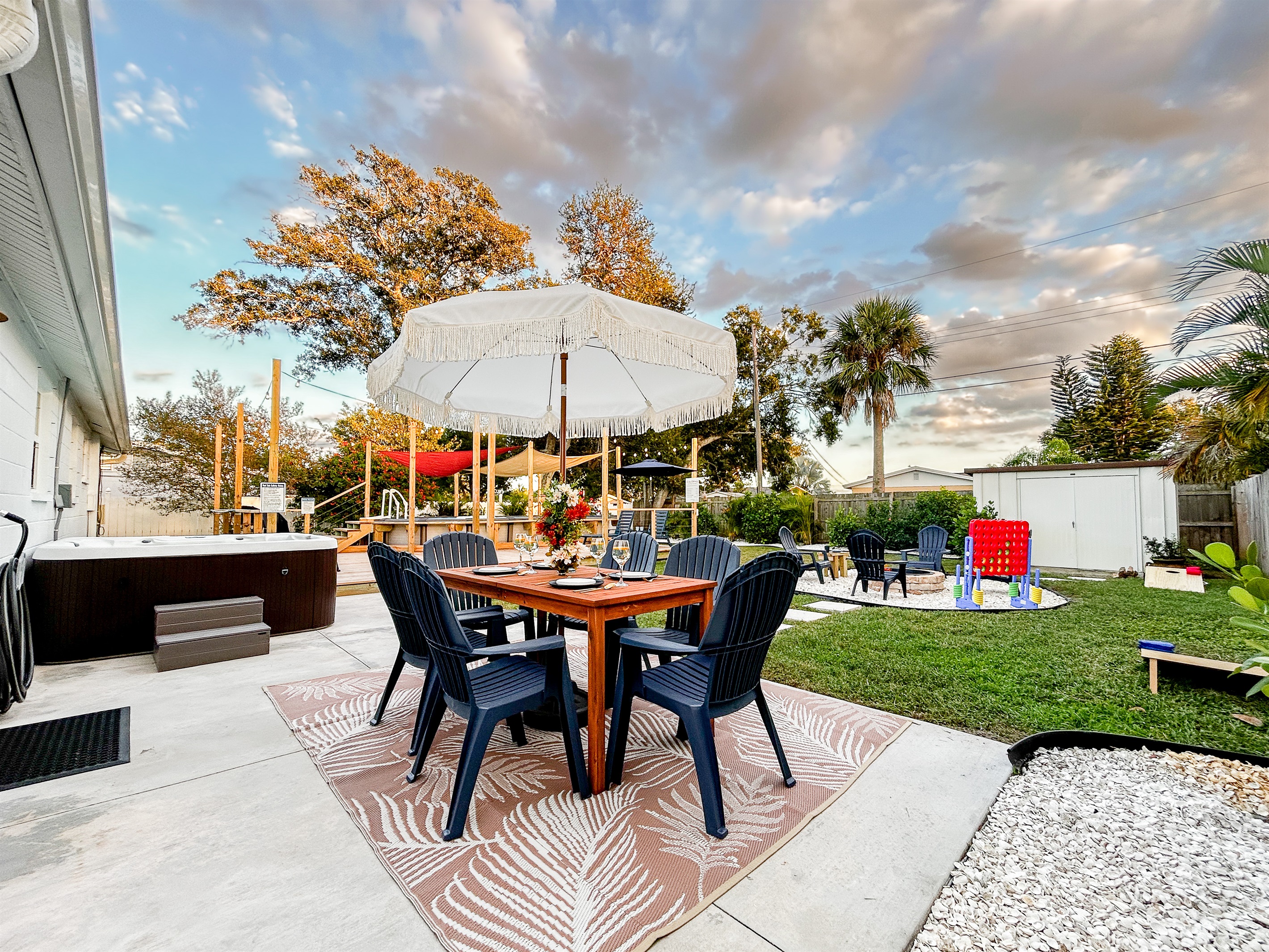 Back Yard with Patio Table with Botanical Umbrella, Hot Tub, Fire Pit, Yard Games, Deck, Full Size BBQ Grill, Sun Loungers, Heated Pool, Sun Shades, Lawn, & More