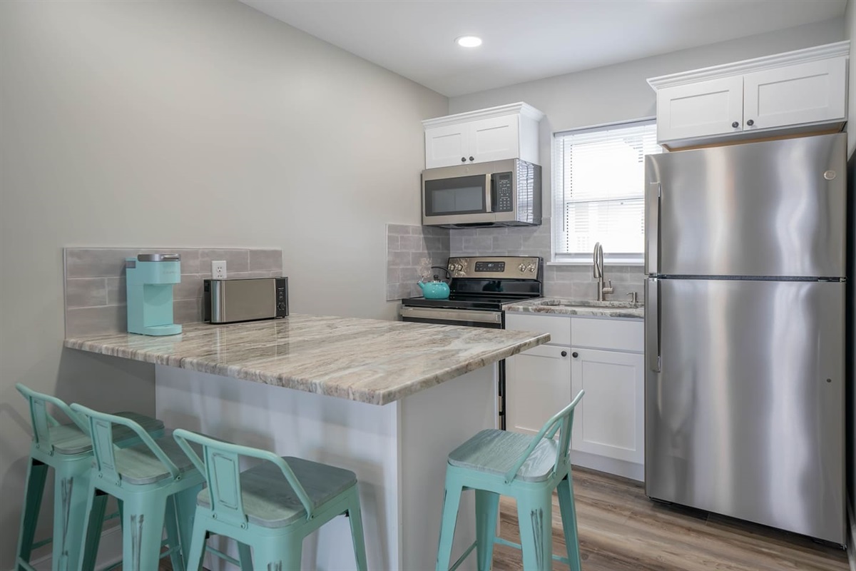 Modern kitchen with full size stainless steel appliances, generous counter space, and a breakfast bar for easy meals. Clean finishes and bright lighting make cooking, coffee breaks, and casual dining simple and comfortable.