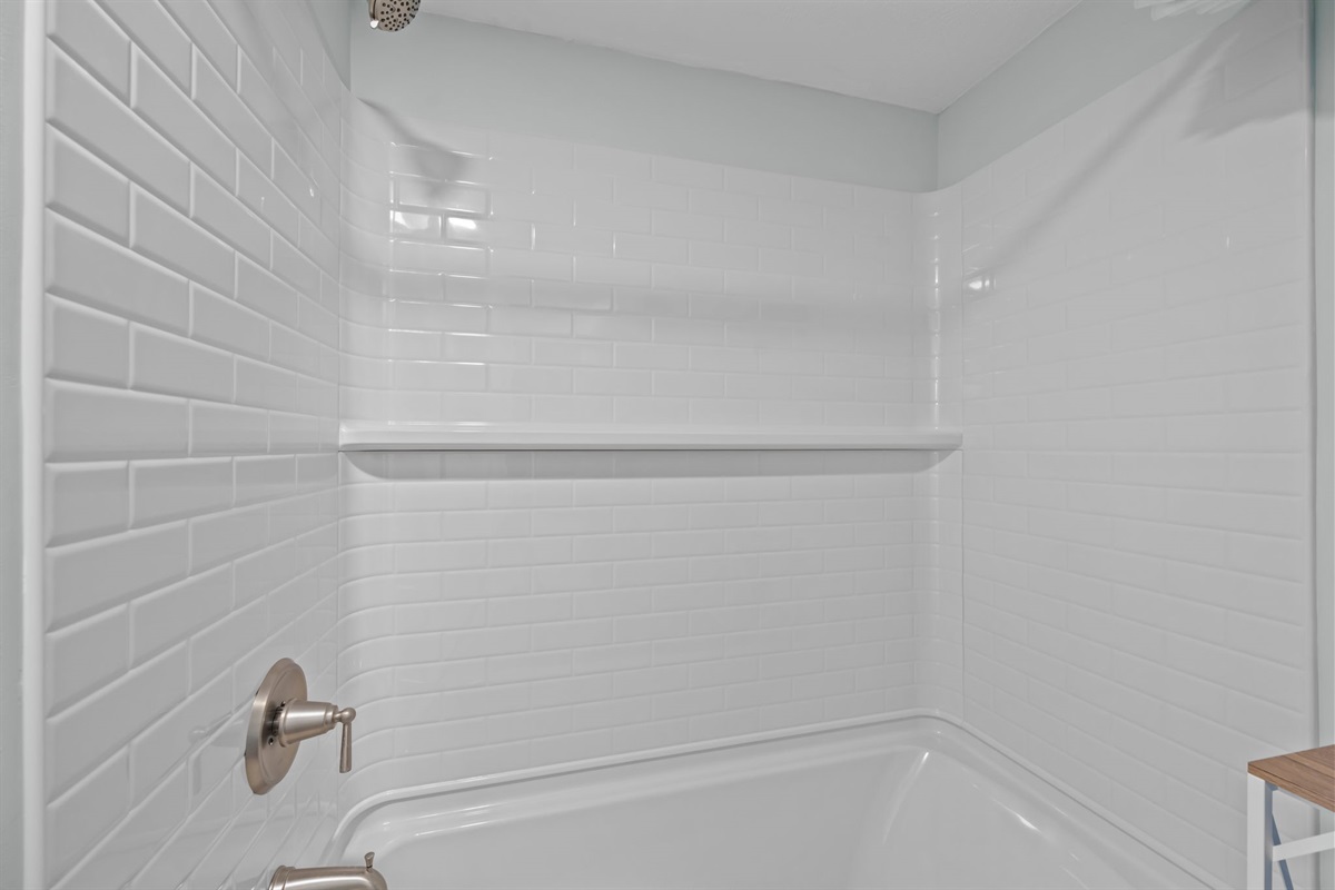 Fresh white tile shower with built-in ledge for convenience