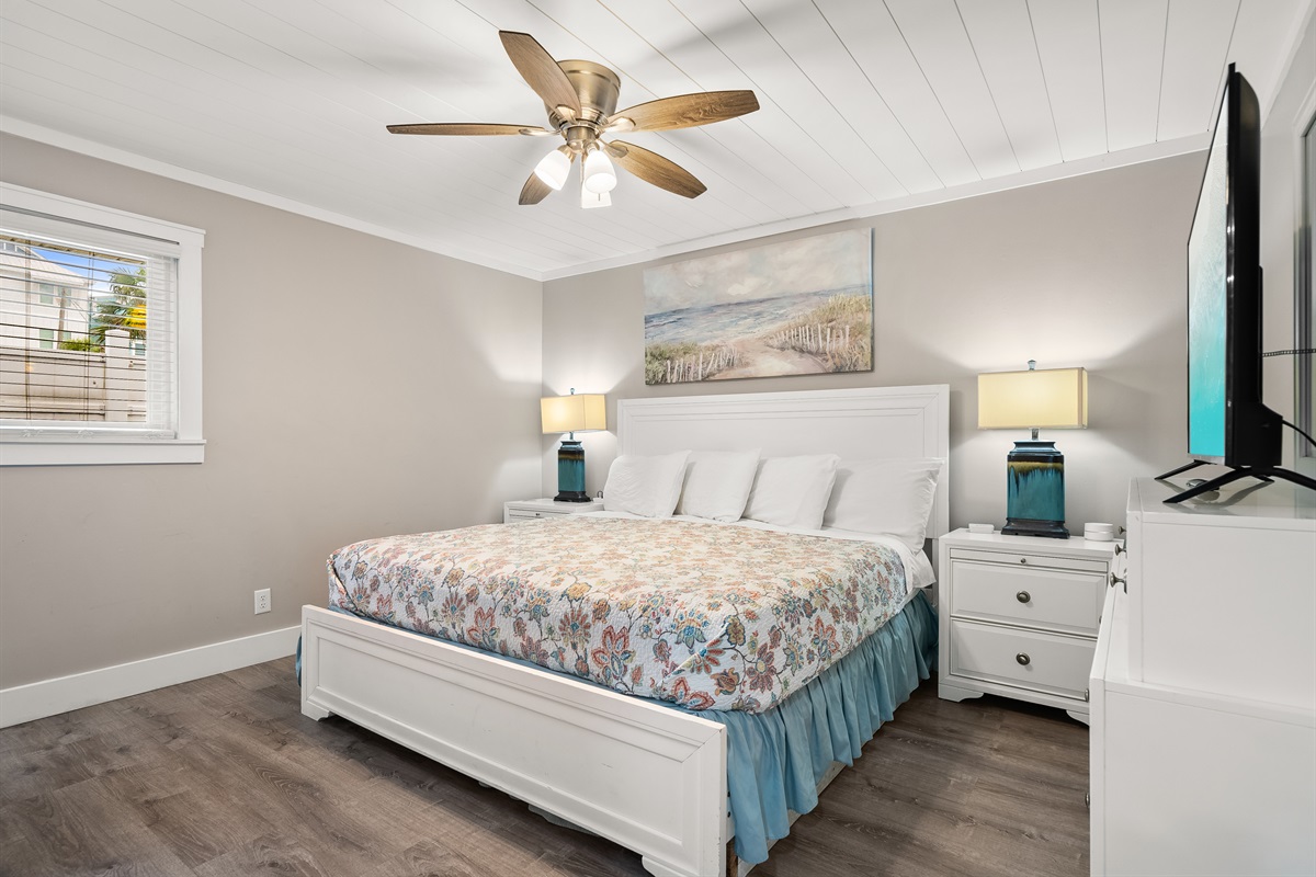 After a fun-filled day on the sugar sand beaches, guests will enjoy the primary bedroom with King bed, television, en suite bathroom, and access to the back porch and pool. 