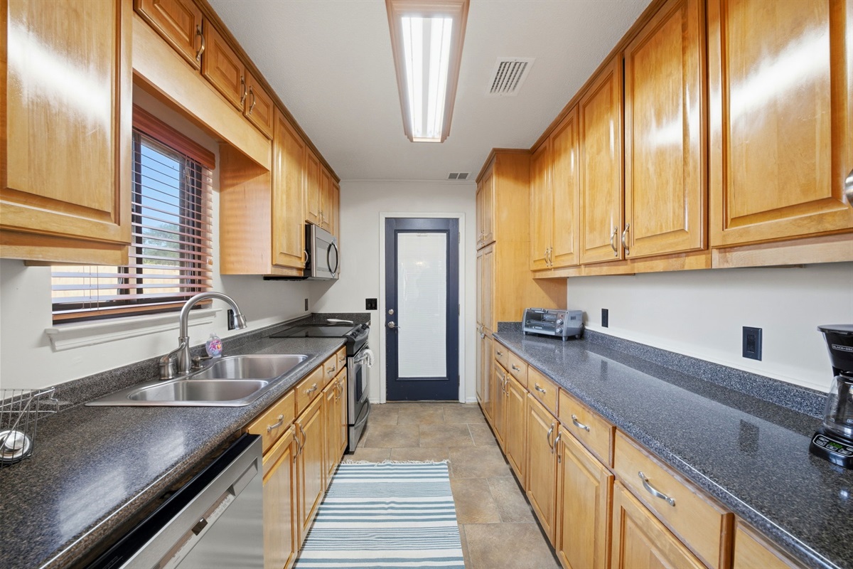 Designed for both efficiency and storage, this spacious kitchen features extensive cabinetry, long countertops, and modern appliances. The layout provides plenty of room to cook, prep, and keep everything neatly organized.