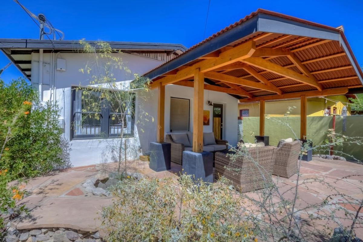 Back patio with seating area and mature desert landscaping