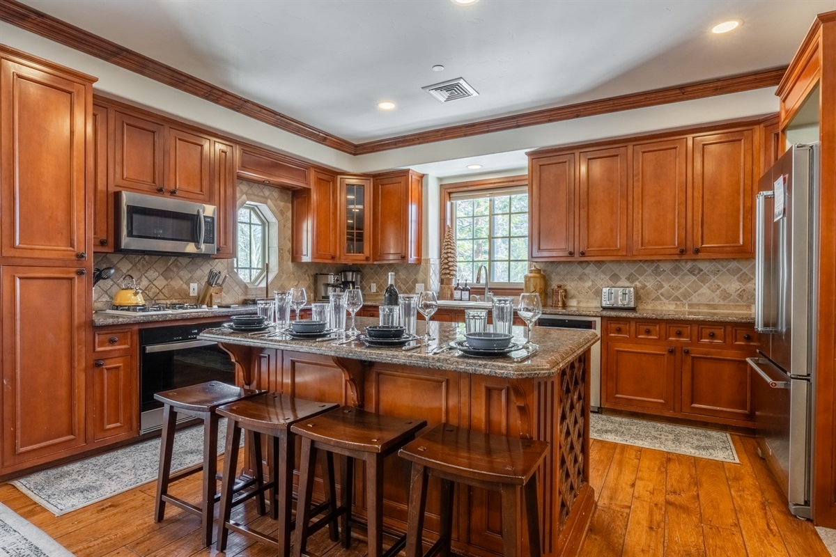 Moose's kitchen with warm wood finishes, granite counters, and a spacious breakfast bar that naturally becomes the hub of the home.