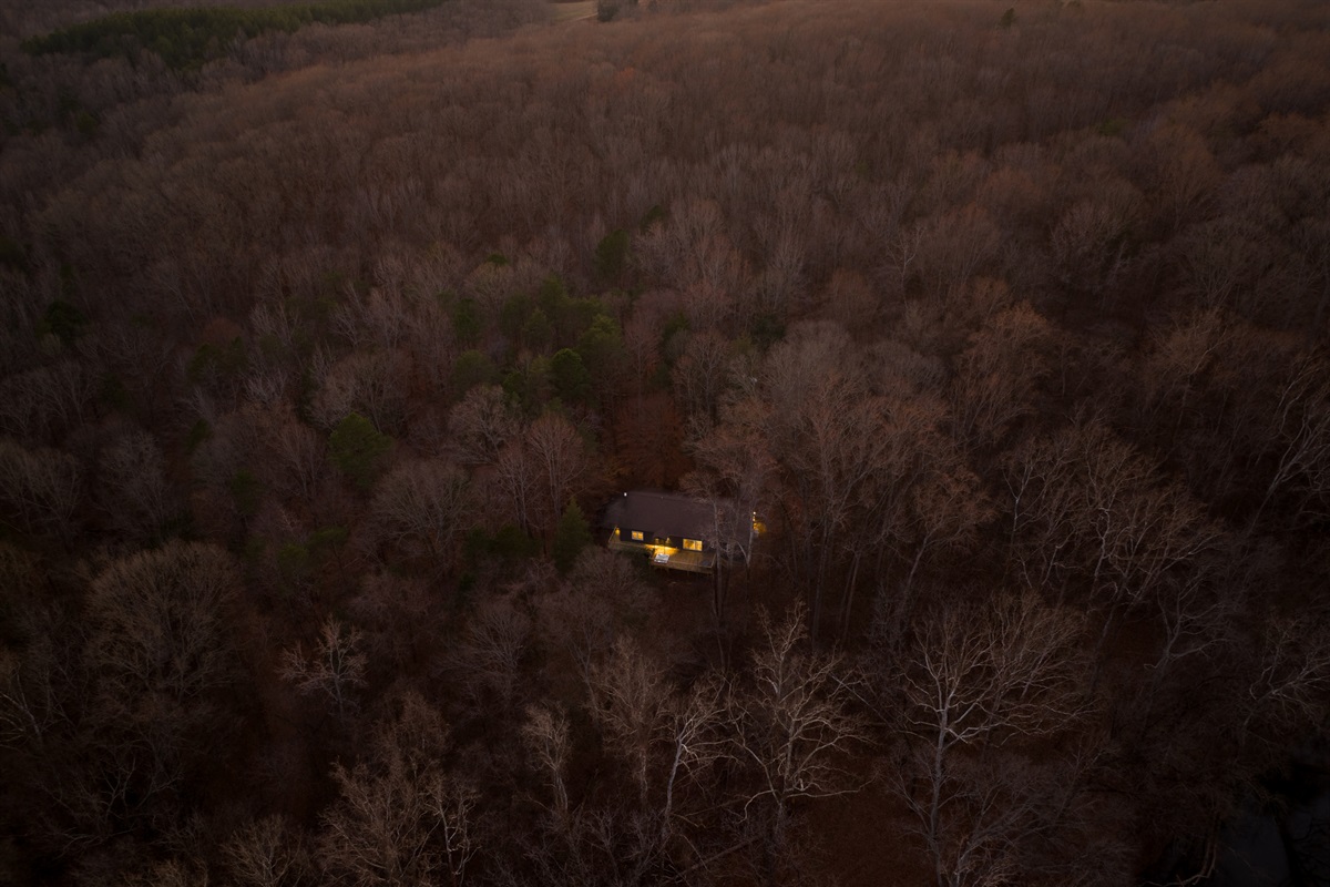 Charming Retreat: Nestled in serene woods, enjoy evening lights beckoning tranquility.