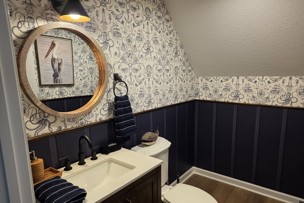 Second-floor powder room near the loft and deck, with stylish wallpaper, warm accents and convenient access.