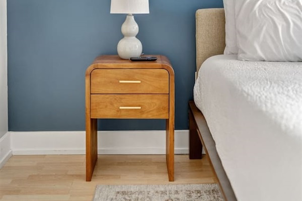 Thoughtful touches add warmth to your stay—soft lighting, modern wood accents, and calming blue walls create a serene bedroom retreat, perfect for winding down after a day in downtown Des Moines.