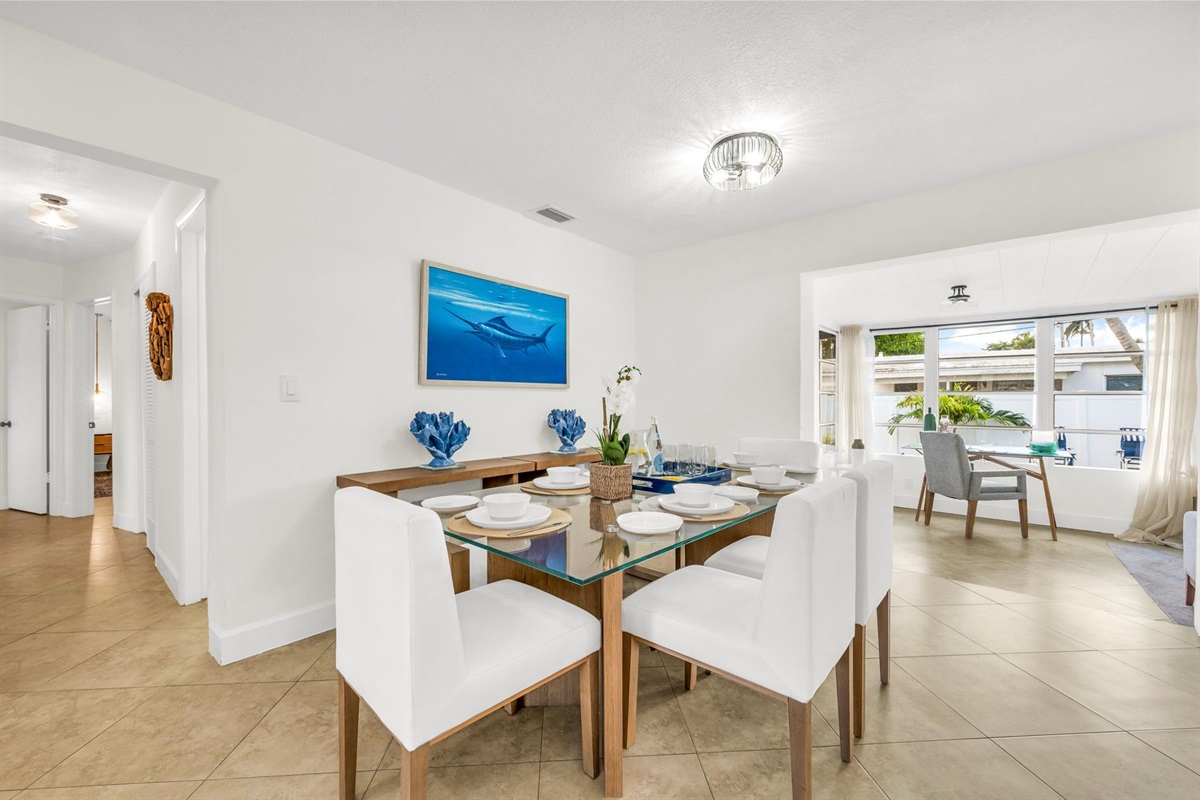 Enjoy meals together in this stylish dining space with seating for six, ocean-inspired artwork, and plenty of natural light flowing in from the adjoining sunroom.
