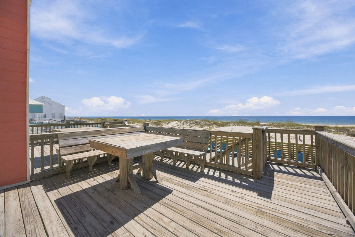 Outdoor deck with dining table and seating overlooking the surrounding beach community, ideal for enjoying meals outdoors.