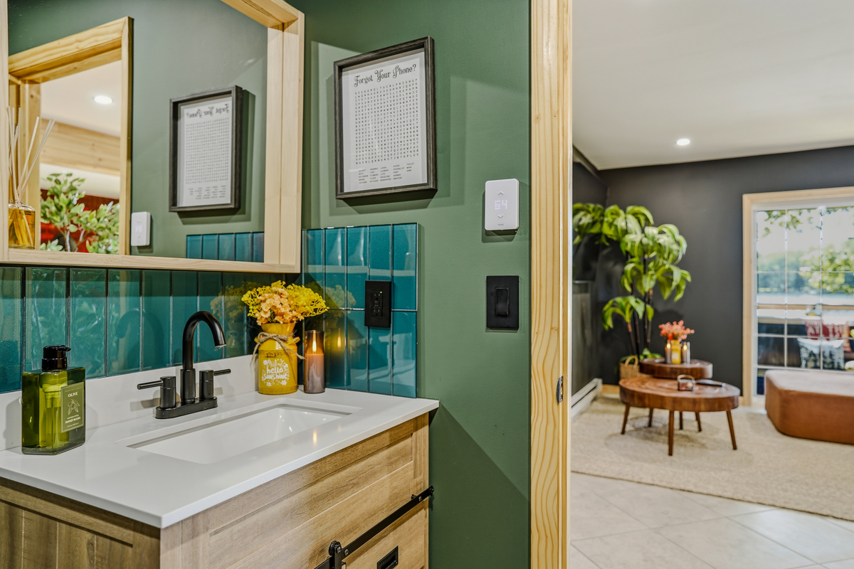 Green-tiled bathroom vanity with warm accent lighting and gold fixtures