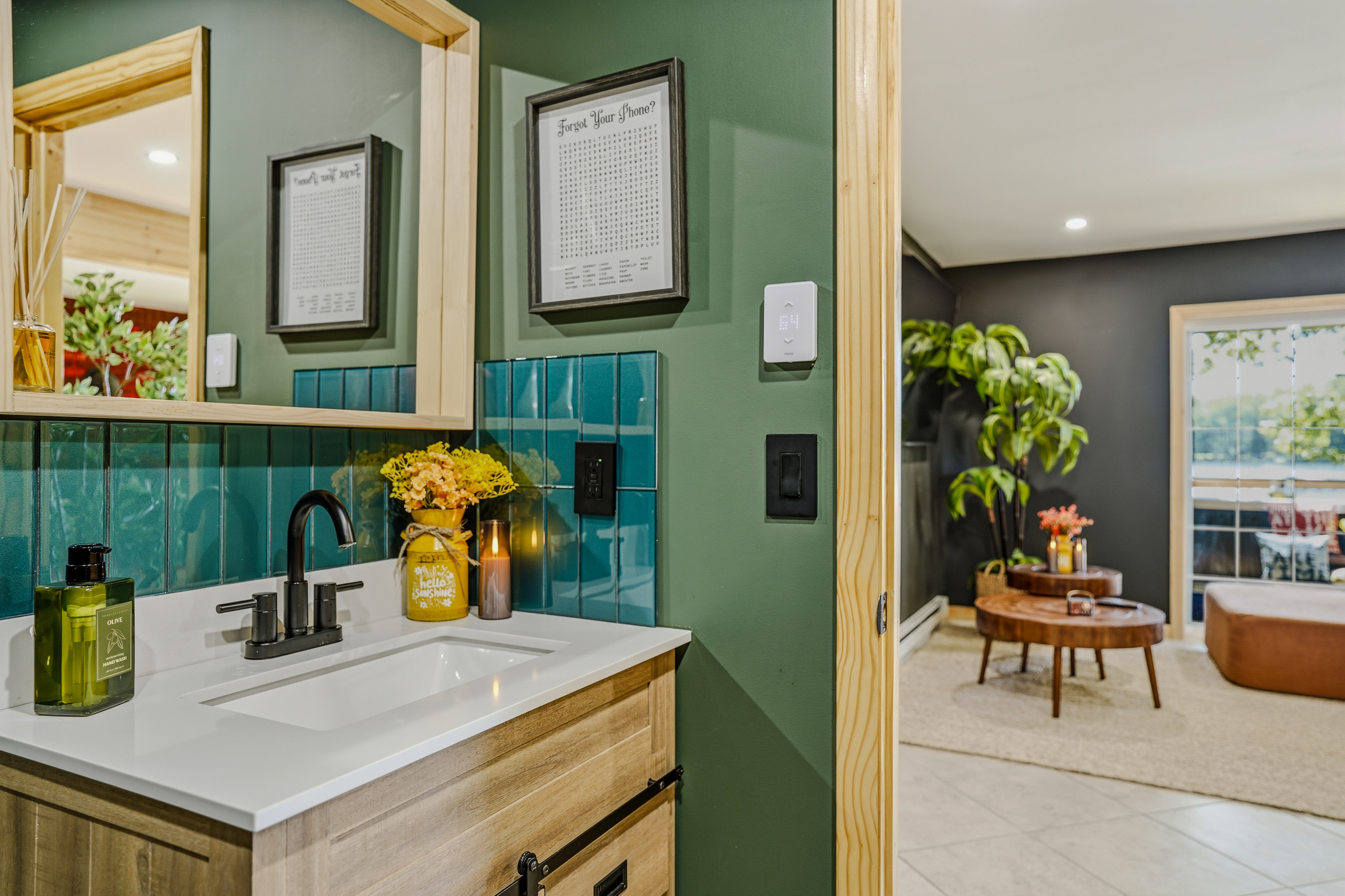 Green-tiled bathroom vanity with warm accent lighting and gold fixtures