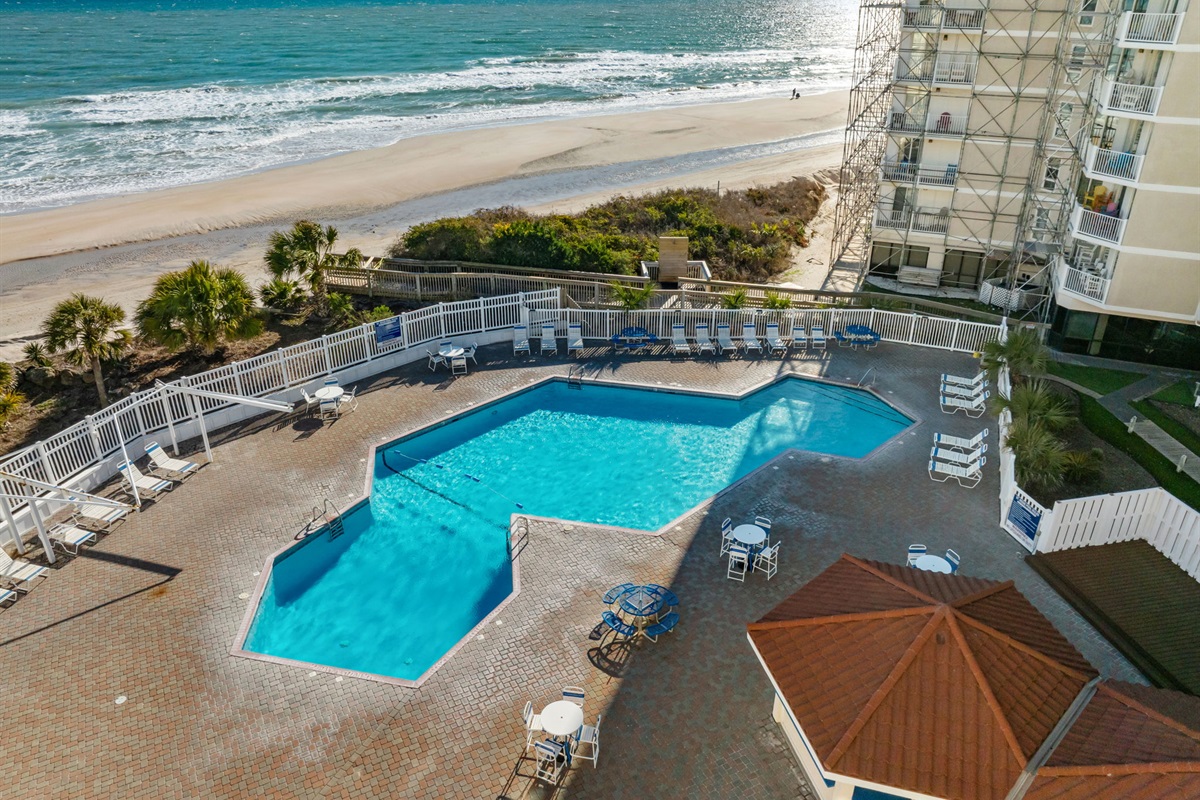 Oceanfront pool deck with spacious seating and stunning views of the shoreline just steps away