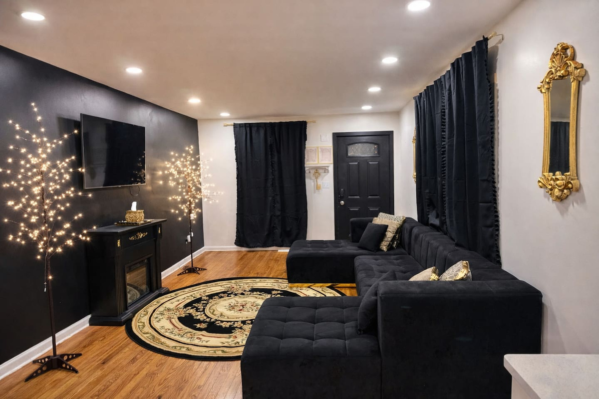 Overview of the living room, featuring blackout curtains, a long sturdy sofa perfect for lounging. Fireplace & Samsung Tv