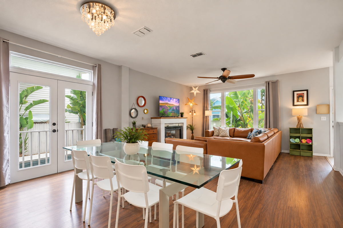 Open dining and living room with a glass table, sectional and fireplace, so meals and game nights share one space.