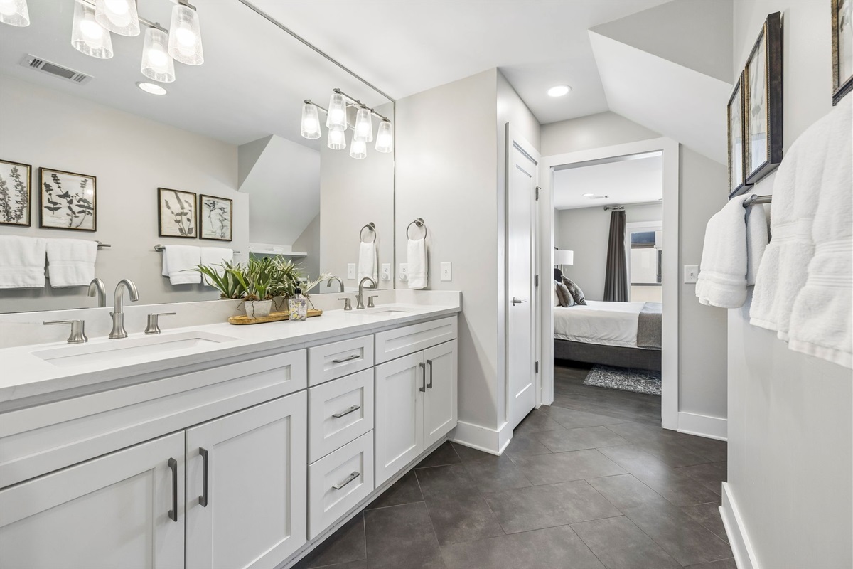 Sleek countertop design with brushed nickel faucet and crisp white quartz surface - Twin faux succulents in rustic pots bring a fresh, natural touch to the bathroom d&eacute;cor - Wood tray base adds texture and warmth to the modern vanity arrangement