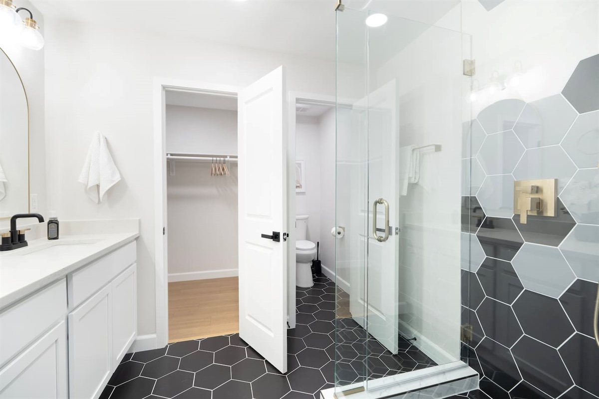 Modern bathroom with a sleek glass walk-in shower, bold tile design, and bright, refreshed finishes—your perfect space to start and end the day
