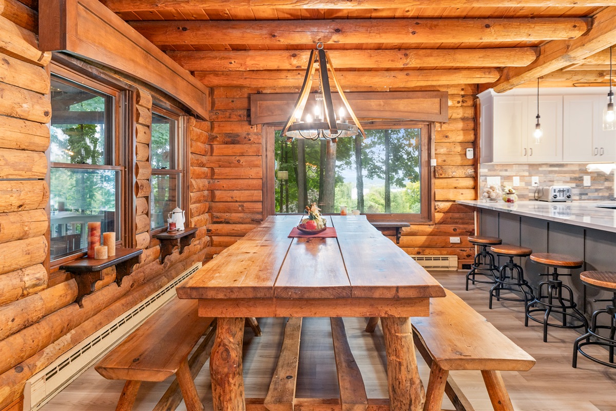 Share meals and memories at the handcrafted farmhouse table with forest views through large cabin windows.