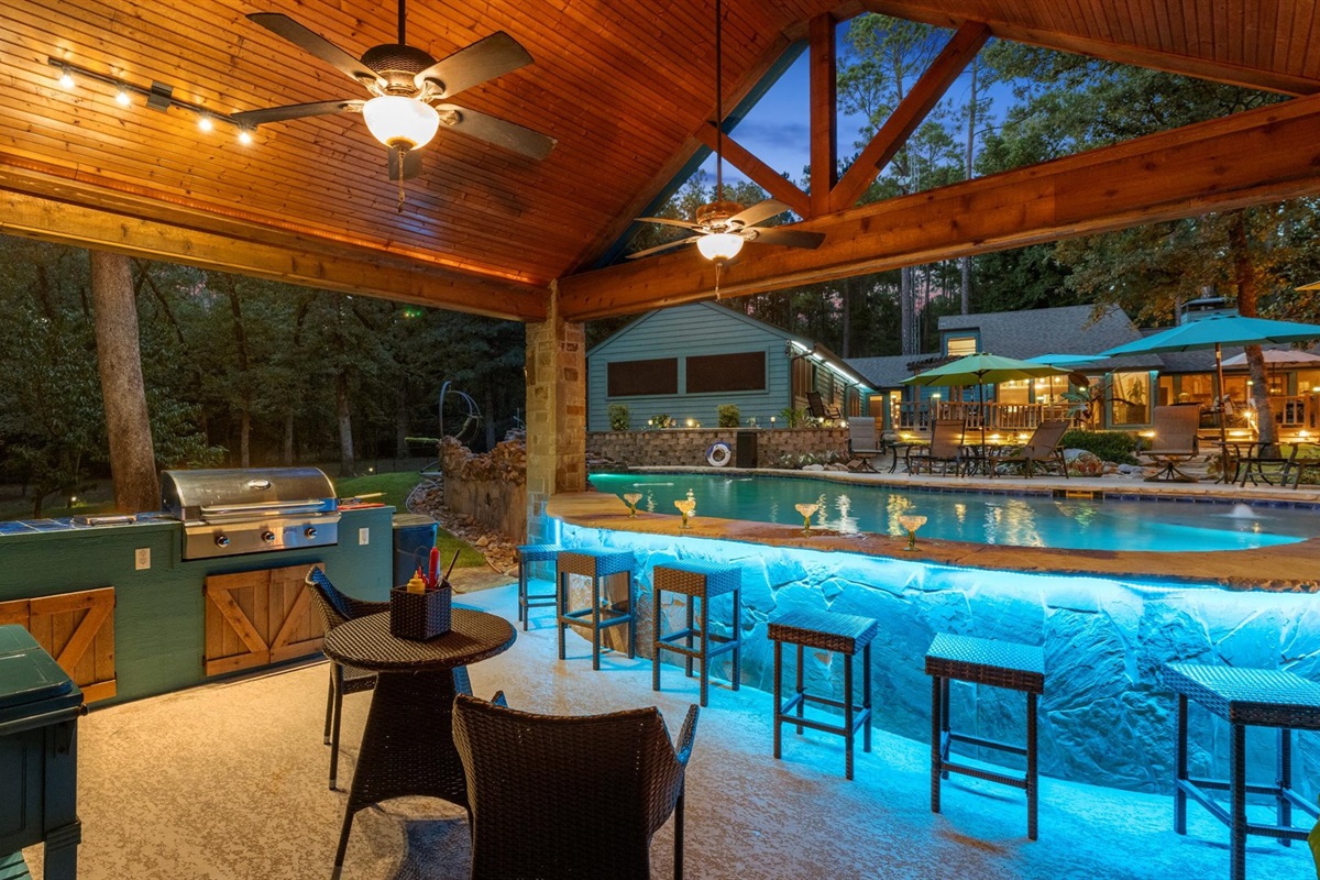 An entertainer’s paradise! This stunning outdoor kitchen and swim-up bar glow beautifully at night, offering the perfect spot to grill, sip drinks, and unwind by the pool in a serene, resort-like setting.