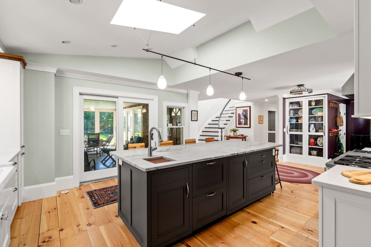 Kitchen with 9 foot island and stools and screened porch beyond.