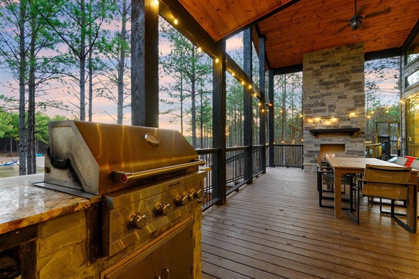 A high-end outdoor kitchen with a stainless steel grill, a stone fireplace, and string lights, offering the perfect ambiance for al fresco dining. This luxury rental feature enhances any vacation experience.