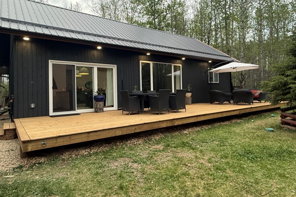 Brand-new 12x44’ front deck with cozy outdoor seating and peaceful forest surroundings.