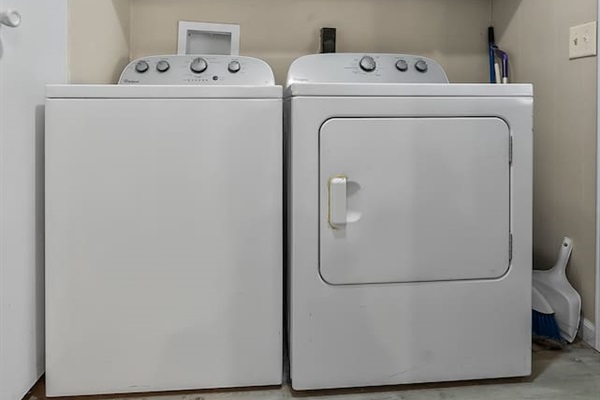 Laundry area with full-size washer and dryer, plus overhead cabinets for convenient storage.
