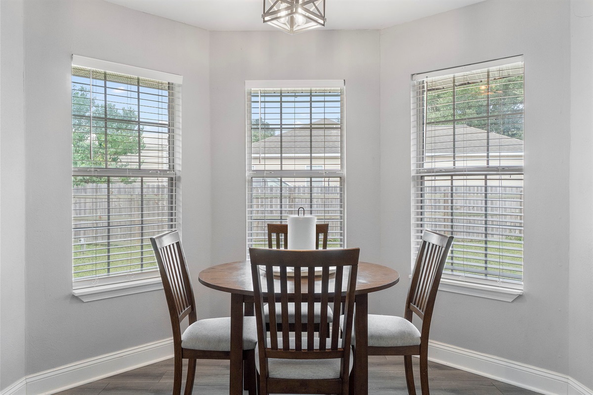 The cozy round dining table nestled in a sunny bay window corner is ideal for relaxed meals, game nights, or planning your next adventure.