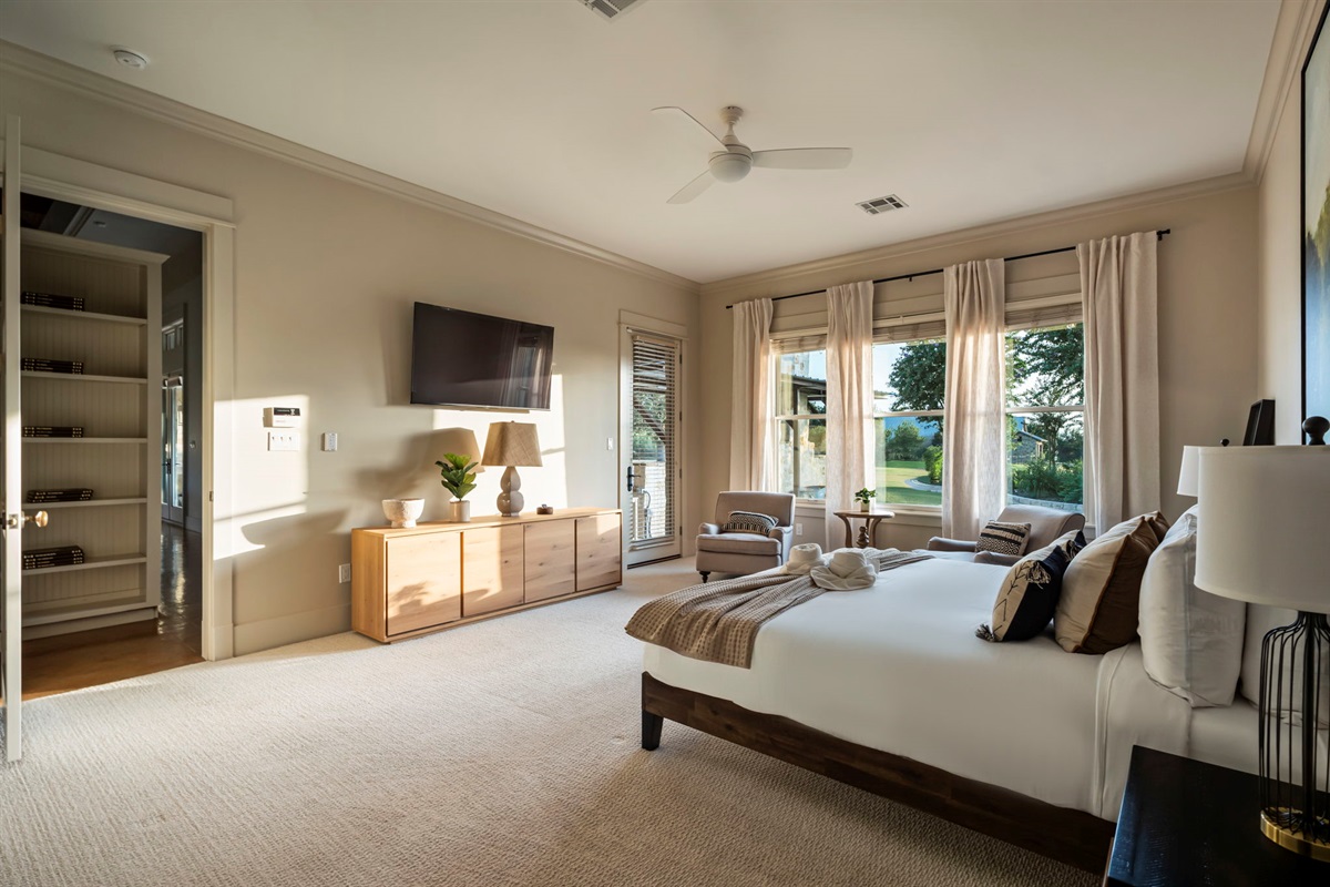 A spacious and serene bedroom retreat featuring a large, wall-mounted TV, perfect for unwinding and enjoying entertainment.