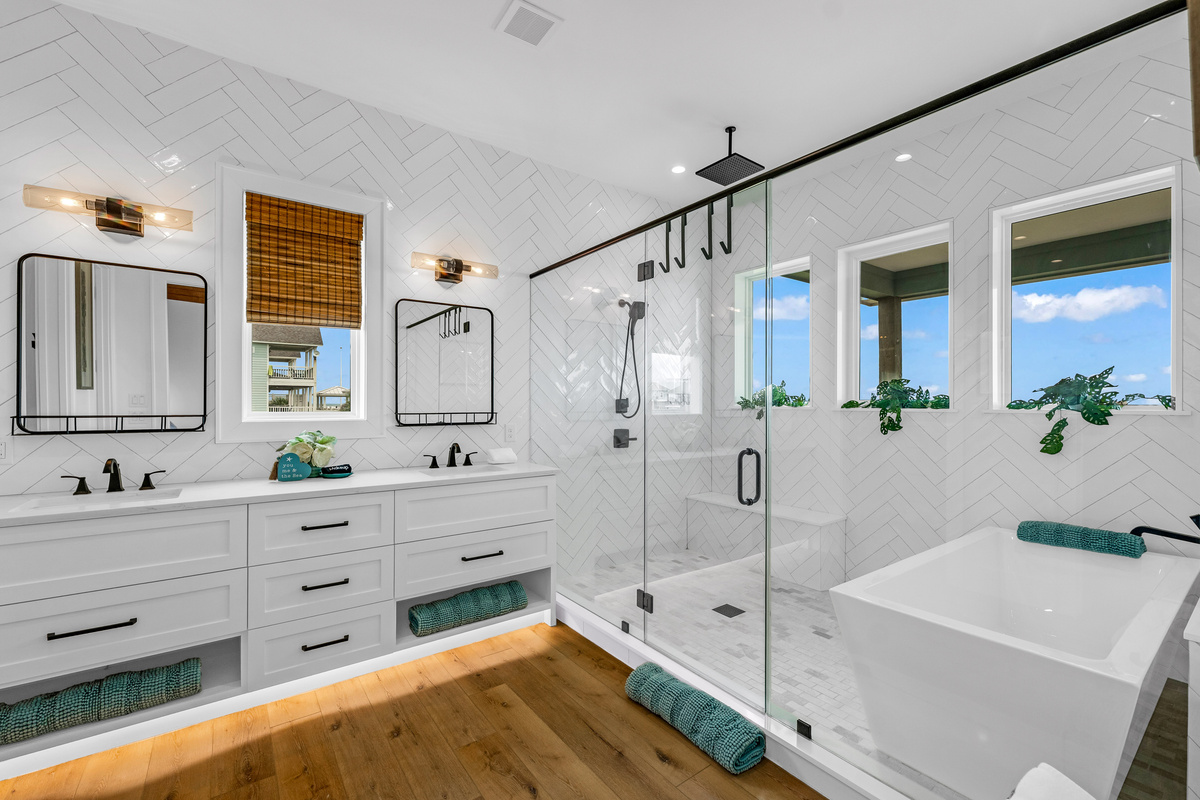 Cair Paravel: Herringbone subway tile and matte black fixtures dress up this ensuite's dual vanity, with a walk-in glass shower just steps away.