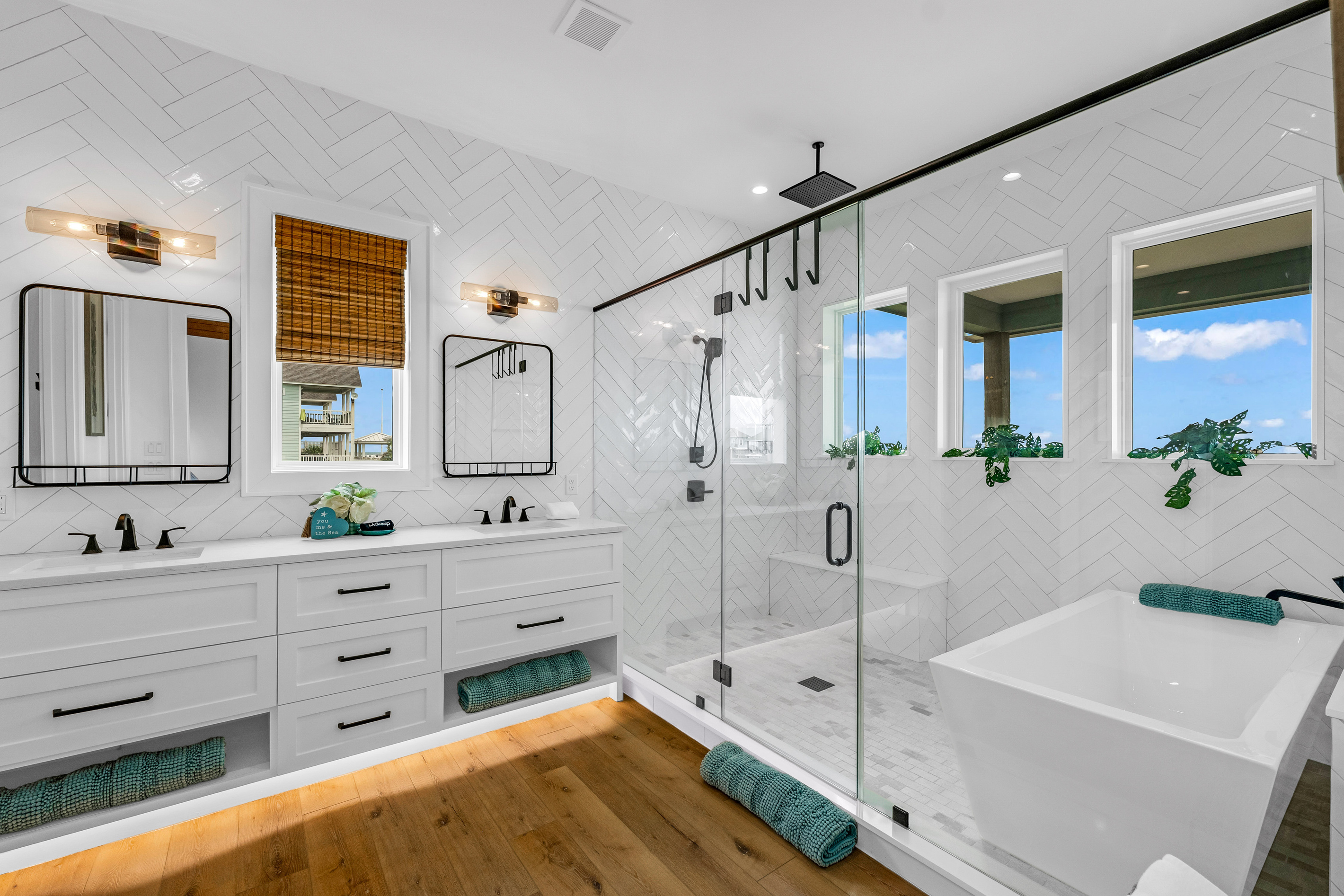 Cair Paravel: Herringbone subway tile and matte black fixtures dress up this ensuite's dual vanity, with a walk-in glass shower just steps away.