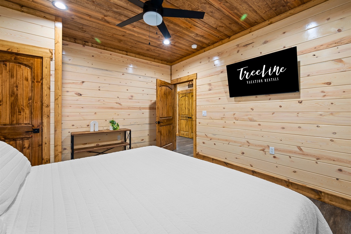 This bedroom continues the cozy cabin feel with wood-paneled walls, a comfortable king bed, and a peaceful setting that makes it easy to settle in for a good night’s sleep.
