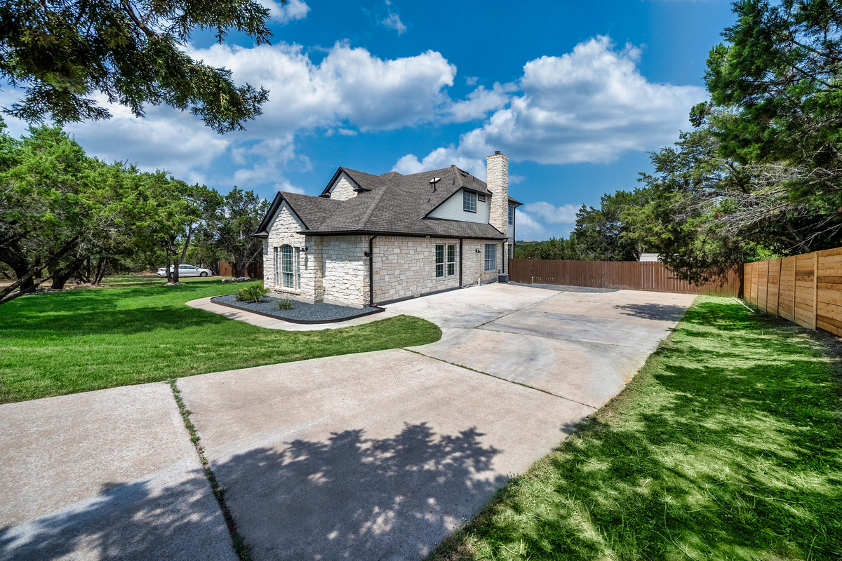 Elegant stone façade framed by an expansive driveway and manicured lawn.