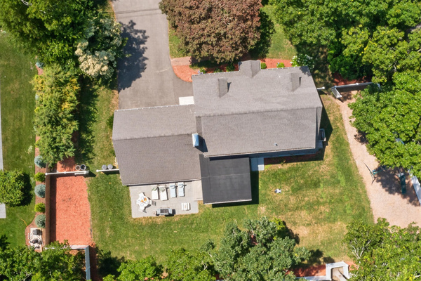 Bird's-eye view of the private backyard with patio, grill, and fully fenced yard.