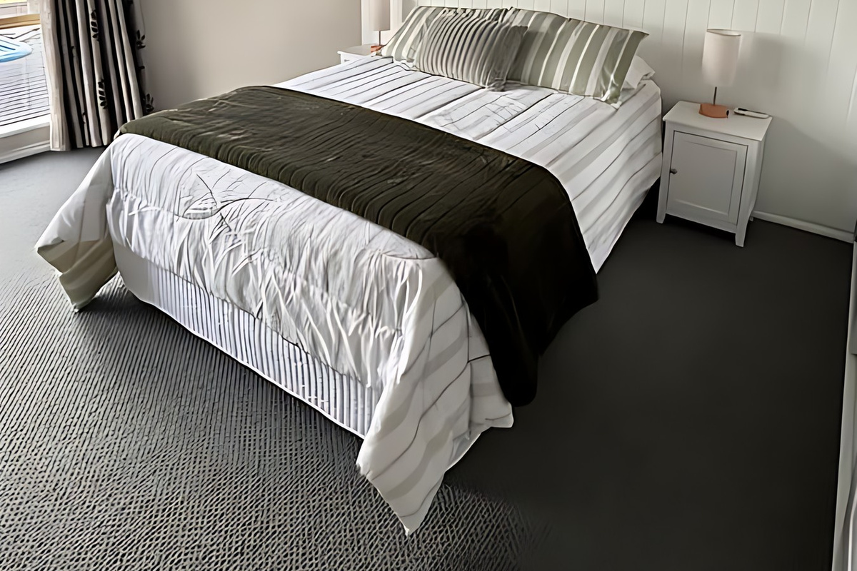 Bedroom 1 at Lake Views & Coastal Escape has a queen bed against a white panelled wall, bedside tables and lamps, a ceiling fan and split-system air conditioning, with its own ensuite.