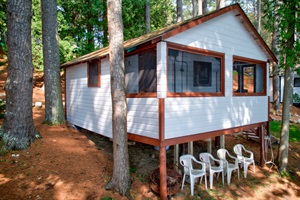 Nestled deep in the woods, this charming white and red cabin offers rustic tranquility with a touch of classic charm