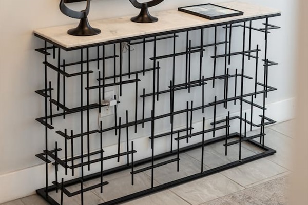 A bold console table with sculptural black decor and vibrant art pieces adds a curated touch to the entry experience.