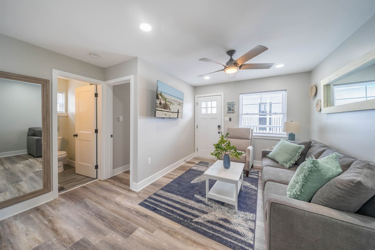 Spacious, light filled living area with comfortable seating, ceiling fan, and smart TV. The open layout connects easily to the kitchen and bathroom, creating a relaxed space to unwind, watch a movie, or settle in between activities.