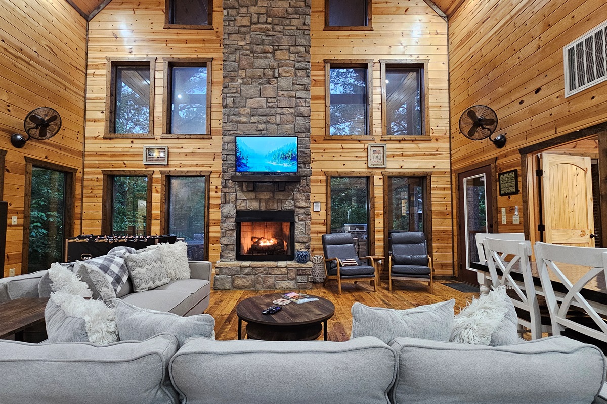 Living Room: Elegant stone fireplace and expansive windows invite nature inside for a memorable stay!