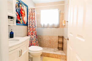 Artistic Sanctuary: Toilet and Sink in a Stylish Bathroom, Elevated by a Striking Painting of a Woman with a Blue Frame, and a Functional Cabinet with Mirror 🚽🖼️🚿