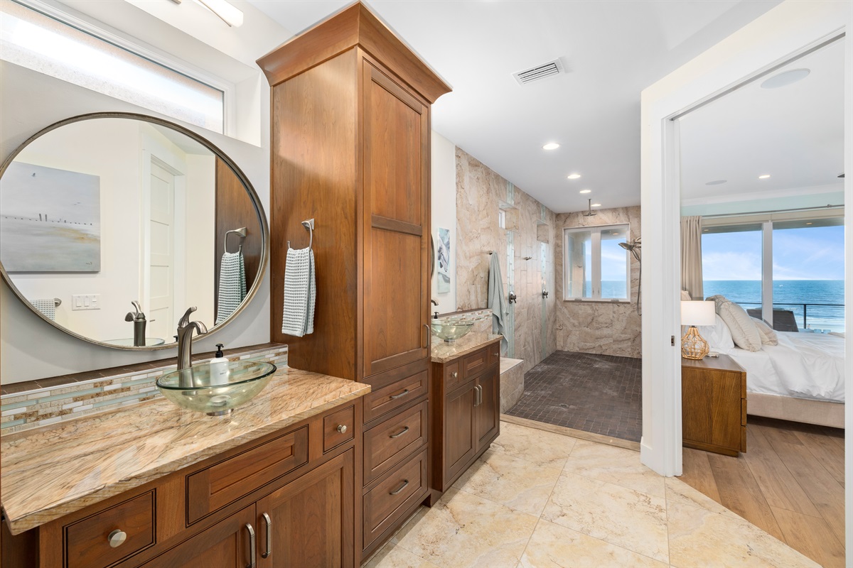 Primary ensuite bath with granite counters, dual vanities, and ocean views