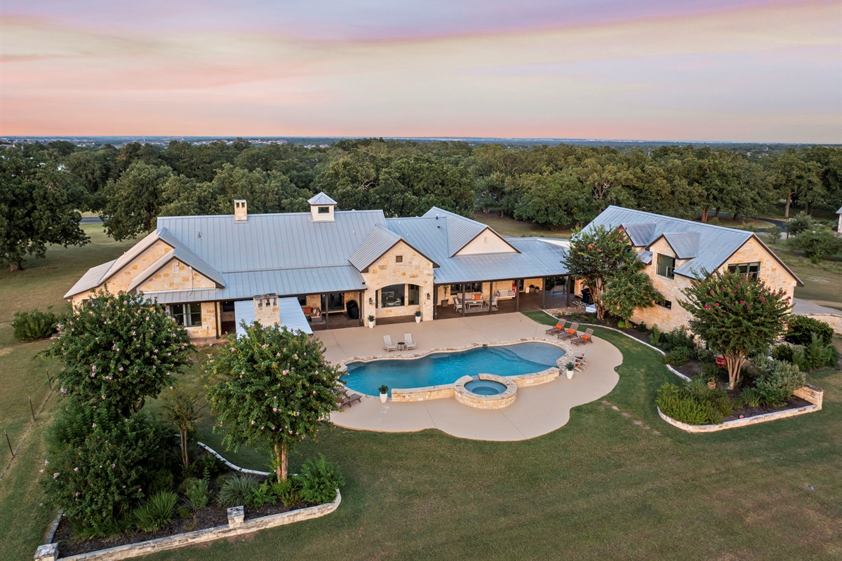 Bird's-eye perspective of a beautiful home and its expansive grounds, featuring a sparkling swimming pool and hot tub.