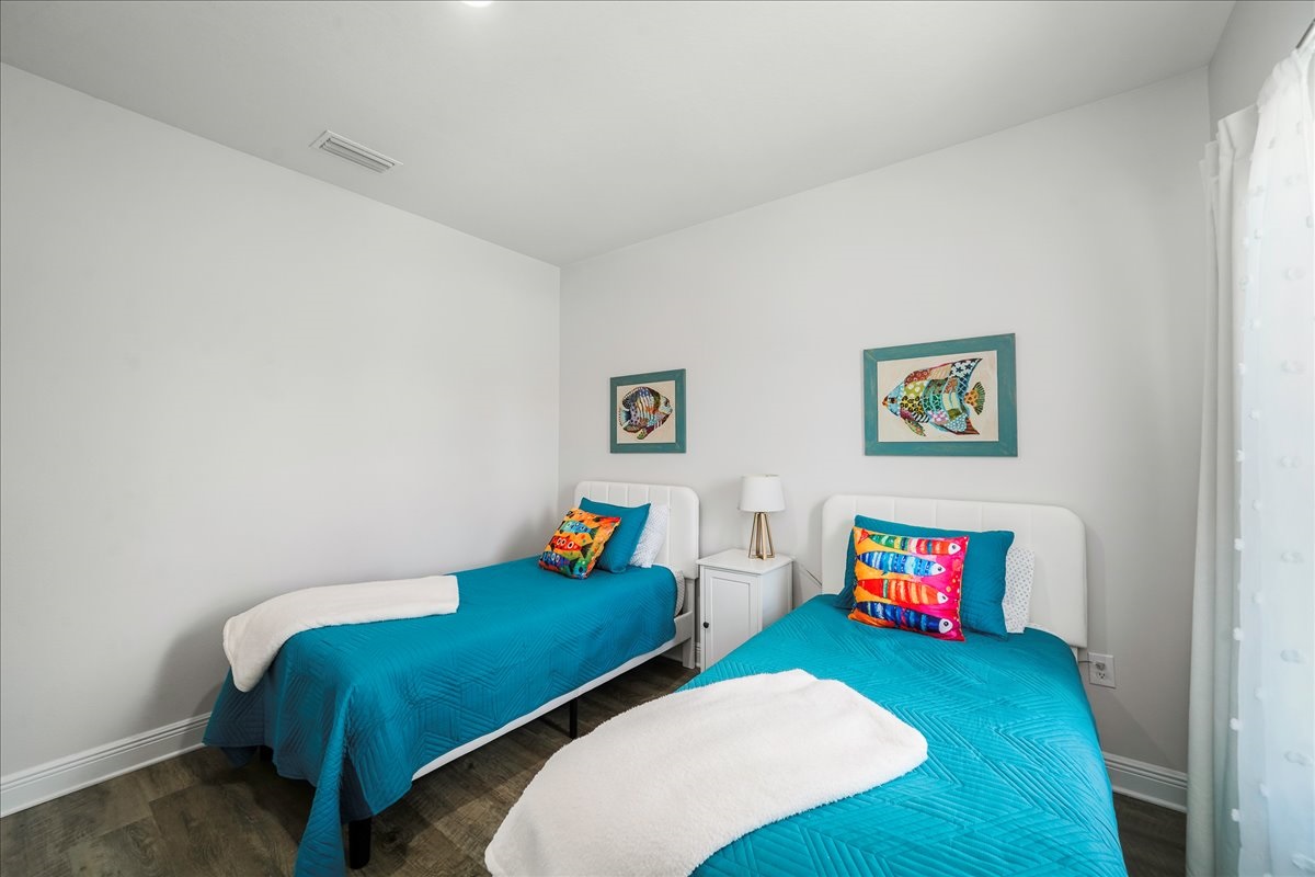 Bedroom 5: twin beds, cozy linens, closet storage, luggage stand, nightstand, and a bedside lamp.