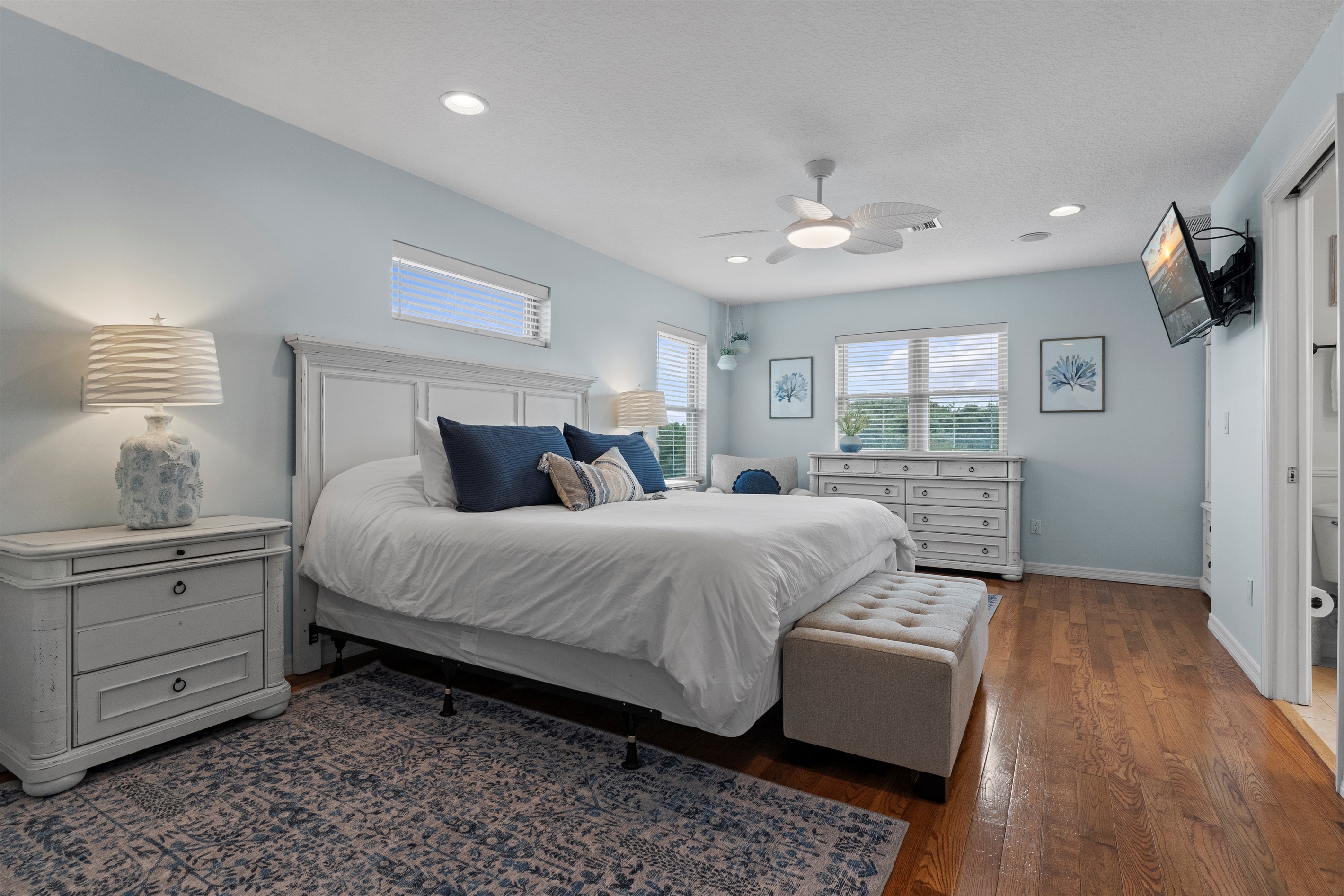 Spacious master ensuite bedroom featuring a smart TV, cozy king-size bed, walk-in closet, chair, dresser, chest, and armoire, with all linens, including pool towels, provided.