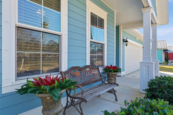 Covered front porch seating at this cheerful coastal vacation home near the beach.