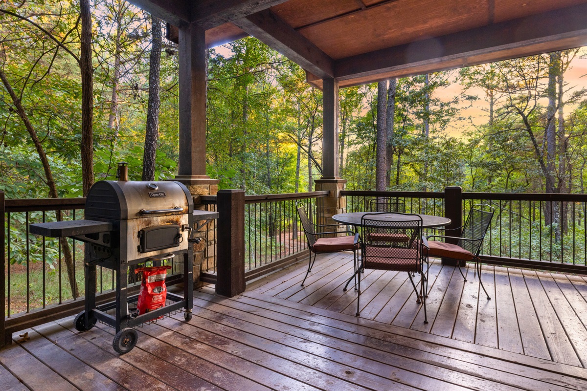 Spacious covered porch with a grill and dining area for outdoor meals in nature.