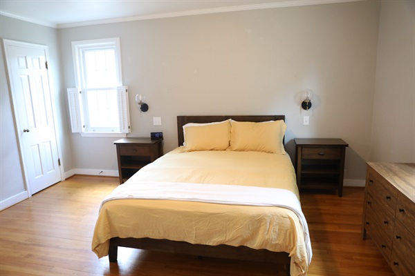 NW Bedroom showing queen size bed, nightstands with alarm clock, wall mounted lamps, and dresser