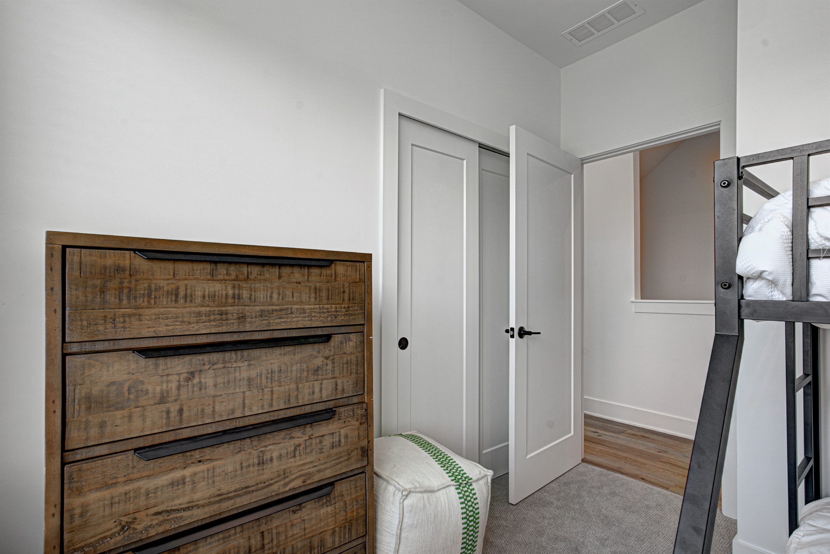Relax in the serene bedroom featuring a comfortable king-size bed, soft linens, and cozy pillows. Includes nightstands, lamps, walk-in closet, and full-length mirror for added comfort.