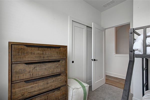 Relax in the serene bedroom featuring a comfortable king-size bed, soft linens, and cozy pillows. Includes nightstands, lamps, walk-in closet, and full-length mirror for added comfort.